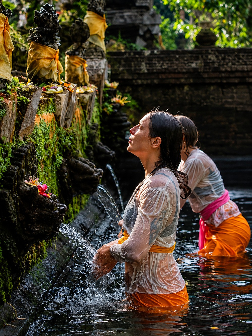 Mulheres em ritual de purificação em fonte sagrada de água em Bali, entre oferendas e estátuas de pedra