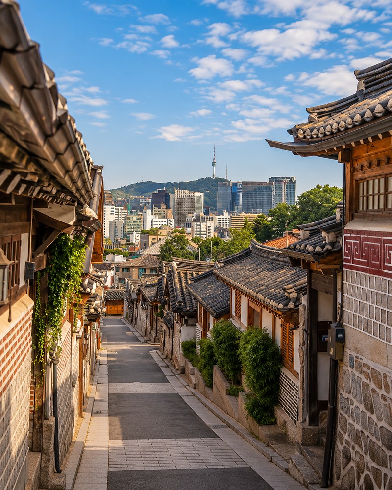 Vila tradicional de Bukchon Hanok, com o skyline de Seul ao fundo