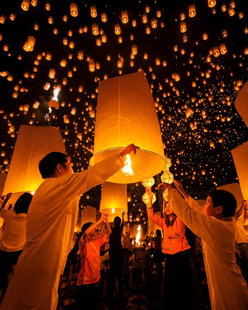 Pessoas soltando lanternas de papel no céu durante um festival tradicional na Tailândia